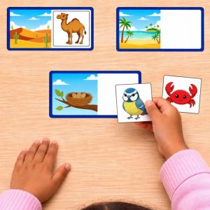 Main d’une enfant plaçant un animal sur son habitat dans un jeu éducatif à imprimer